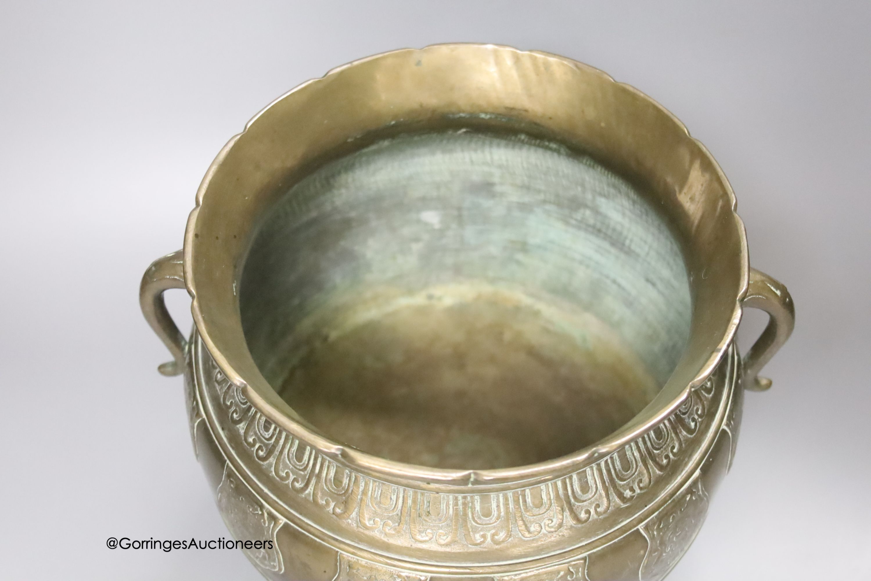 A Chinese or Japanese bronze two handled vessel, on cast feet, 22cm